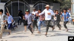 Cambodian garment workers run for safety in front of a factory of Yak Jin in Kambol village on the outskirts of Phnom Penh, Cambodia, Jan. 2, 2014.