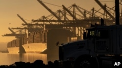 FILE - A truck arrives to pick up a shipping container near vessels moored at at the Port of Los Angeles, on Nov. 30, 2021. President Joe Biden is expected to unveil plans for substantial tariff increases on selected Chinese imports in the coming days.
