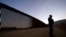 FILE - Border Patrol agent Justin Castrejon stands in front of newly replaced border wall sections, near Tecate, California, Sept. 24, 2020.