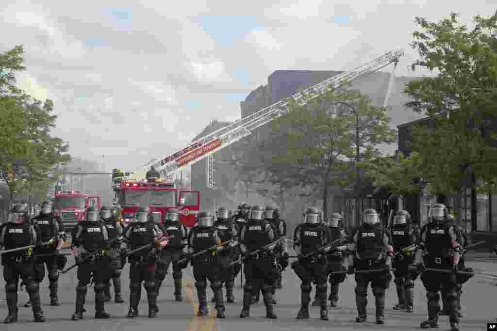 ប៉ូលិស​រដ្ឋ​&nbsp;Minnesota&nbsp;ឈរ​ការពារ ខណៈ​ក្រុម​អ្នក​ពន្លត់​ភ្លើង​កំពុង​ពន្លត់​ភ្លើង​កាលពីថ្ងៃទី២៩ ខែឧសភា ឆ្នាំ២០២០។ ពលរដ្ឋនាំគ្នា​ធ្វើបាតុកម្ម​ប្រឆាំង​នឹង​ការ​ចាប់​ខ្លួន​លោក&nbsp;George Floyd&nbsp;ដែល​បាន​ស្លាប់​ពេល​ប៉ូលិស​ឃាត់​ខ្លួន​កាលពី​យប់​ថ្ងៃច័ន្ទ​នៅ​ទីក្រុង&nbsp;Minneapolis។&nbsp;(រូបថត AP) 