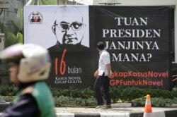 Seorang pria melihat poster di depan kantor KPK menyambut kembalinya penyidik Novel Baswedan, 27 Agustus 2018. Masyarakat mendesak Presiden Jokowi untuk membentuk tim pencari fakta dalam menyelesaikan kasus itu saat Novel kembali bekerja 16 bulan setelah