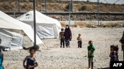 Perempuan dan anak-anak tampak di depan kamp di provinsi Hasakah setelah direlokasi dari kamp pengungsi al-Hol, Suriah (foto: dok). 