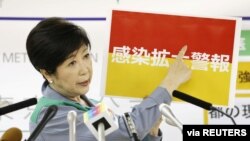 Gubernur Tokyo Yuriko Koike memperlihatkan spanduk merah bertuliskan 'Peringatan Penyebaran Infeksi (Covid-19)' dalam konferensi pers terkait perkembangan Covid-19 di Tokyo, Jepang, 15 JUli 2020. (Foto: Kyodo).