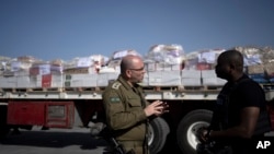 FILE - Israeli Army Colonel Moshe Tetro speaks to a journalist as trucks carrying humanitarian aid bound for the Gaza Strip wait in a holding area at Kerem Shalom Crossing on the border between Gaza and southern Israel on Jan. 10, 2024.