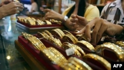 Picture taken on September 1, 2010 shows Myanmar vendors arranging a display of gold jewellery at a jewellery shop at Chinatown in downtown Yangon. Housewives huddle over jewellery counters in Yangon's bustling Chinatown -- but they do not have fashion o