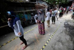 Warga menjaga jarak aman saat antre untuk mendapatkan bantuan makanan di tengah pandemi virus corona, di sebuah kampung di Jakarta, 22 April 2020. (Foto: AP)