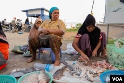 Khmer Islam fish seller Sos Nob, 48, sits beside her niece in front of the Sokha ferry entrance on the evening of Oct. 14, 2019 in Phnom Penh, Cambodia. (Malis Tum/VOA Khmer)