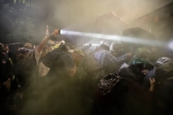 Demonstrators push on a fence as tear gas is deployed during a Black Lives Matter protest at the Mark O. Hatfield United States Courthouse, July 25, 2020, in Portland, Oregon.