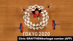 Atlet Indonesia Windy Cantika Aisah saat berlaga di cabang olahraga angkat besi 49 kg putri di Olimpiade Tokyo 2020, 24 Juli 2021. (Foto: Chris GRAYTHEN/berbagai sumber/AFP)