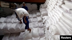 Para pria memuat karung beras ke kapal di sebuah pabrik pengolahan beras di Delta Mekong selatan Vietnam untuk diekspor, Vietnam, 6 Juli 2017. (Foto: REUTERS/Kham)