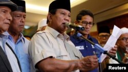 Kandidat presiden Indonesia, Prabowo Subianto memberikan pidato untuk menyatakan kemenangan pemilu saat pasangannya Sandiaga Uno berdiri di sebelahnya di Jakarta, Indonesia, 18 April 2019.