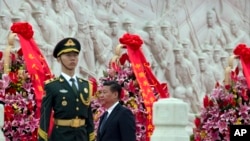 中国主席习近平在北京的人民英雄纪念碑前向烈士致敬后走过纪念碑(2014年9月30日)