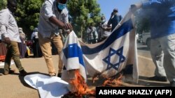 Warga yang marah membakar bendera Israel untuk memrotes normalisasi hubungan Sudan-Israel dalam aksi di Khartoum (foto: dok). 