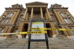 Police tape is wrapped around a sign in front of a closed entrance at the Statehouse in Des Moines, Iowa, March 16, 2020. Iowa leaders are suspending the legislative session for at least 30 days because of the coronavirus.