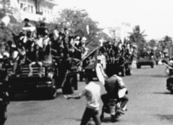 Flag-waving and jubilating Red Khmer soldiers enter the city of Phnom Penh on their trucks, April 17, 1975, when this Cambodian capital surrendered to the Khmer Rouge. Civilians pass the truck convoy on their motor scooters. (AP Photo)