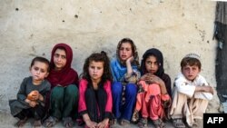 Anak-anak duduk di depan sebuah rumah di desa Deh Qubad di distrik Maiwand, Provinsi Kandahar, Afghanistan, 27 September 2020. (Foto: AFP)