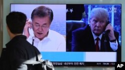 Seorang pria berjalan melewati layar televisi yang menayangkan berita peluncuran misil Korea Utara dengan gambar Presiden Amerika Serikat Donald Trump dan Presiden Korea Selatan Moon Jae-in di Stasiun Kereta Seoul, Korea Selatan, Jumat, 1 Desember 2017.