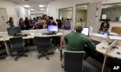 FILE - U.S. Customs and Border Protection agents work at a processing facility in Brownsville,Texas, June 18, 2014. A new "surge initiative" aims to identify and arrest the adult sponsors of unaccompanied minors who paid smuggling operations to bring young people across the U.S. border, Immigration and Customs Enforcement officials confirmed, June 29, 2017.