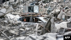Sebuah kendaraan bergerak melewati reruntuhan bangunan yang runtuh di Khan Yunis di Jalur Gaza selatan pada 16 September 2024. (Foto: AFP)