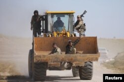 Fighters from the Syrian Democratic Forces sit in the bucket of an excavator in the village of Baghuz, Deir el-Zour province, Syria, March 20, 2019.
