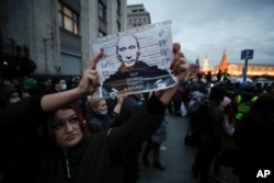 Seorang perempuan mengangkat gambar Presiden Rusia Vladimir Putin yang bertuliskan 'Haruskah pencuri berada di Kremlin?' saat unjuk rasa mendukung politisi oposisi Rusia Alexei Navalny yang dipenjara di Moskow, Rusia, 21 April 2021. (Foto: REUTERS/Maxim Shemetov)