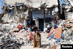 Warga Palestina duduk di tengah reruntuhan bangunan yang hancur selama serangan Israel, di tengah gencatan senjata antara Israel dan Hamas, di Rafah di Jalur Gaza selatan, 16 Februari 2025. (Hatem Khaled/REUTERS)