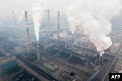 FILE - Pollution is emitted from steel factories in Hancheng, Shaanxi province, Feb. 17, 2018.