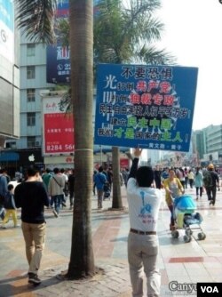 黄文勋举着一块足有一平方米大的标语牌走上了深圳人流熙攘的大街（2013年3月10日）