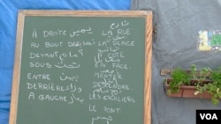 Words in Arabic and French are seen on a chalk board at a migrant school in the Jungle camp in Calais, France. (L. Bryant/VOA)