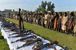 Para kombatan ISIS dan senjata yang disita setelah mereka menyerahkan diri kepada pemerintah Afghanistan, di Jalalabad, Provinsi Nangarhar, 17 November 2019. (Foto: AFP)