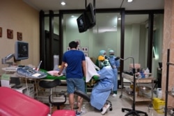 Dokter kandungan-ginekologi Ika Sri Purnamaningsih (tengah) dan perawat memakai alat pelindung saat memeriksa ibu hamil di RSIA Tambak, Jakarta, 22 April 2020. (Foto: AFP/Adek Berry)