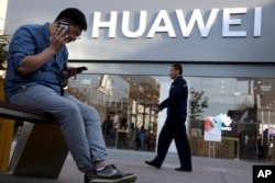 A man uses two smartphones at once outside a Huawei store in Beijing, May 20, 2019.