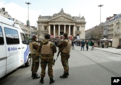 Belgian soldiers stand guard next to one of the memorials to the victims of the recent Brussels attacks, at the Place de la Bourse in Brussels, March, 27, 2016.