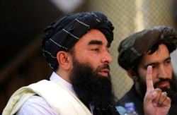 Juru bicara Taliban Zabihullah Mujahid, kiri, berbicara pada konferensi pers pertamanya di Pusat Informasi Media Pemerintah, di Kabul, Afghanistan, Selasa, 17 Agustus 2021. (Foto: AP)