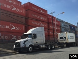 Cargo containers line the Delaware River as a truck sits idly by the roadside, in Philadelphia, June 2016. (A. Pande / VOA)