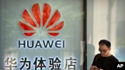 一名男子在北京一家购物中心的华为专卖店外使用智能手机。（2019年5月29日）