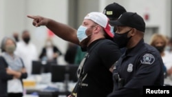 Policija Detroigta sprovodi čoveka koji osporava glasanje, nakon što je odbio da izađe što mu je naloženo zbog malog kapaciteta prostora, u TCF cnetru nakon izbornog dana u Detroitu, 4. novembra 2020.