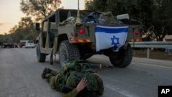 Izraelski vojnik se sakriva iza vozila (Foto: AP/Ohad Zwigenberg)