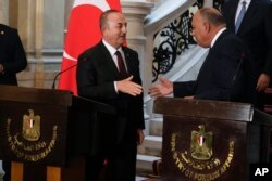 Menteri Luar Negeri Mesir Sameh Shoukry (kanan) bersalaman dengan Menteri Luar Negeri Turki Mevlut Cavusoglu usai konferensi pers di Istana Tahrir, Kairo, Mesir, 18 Maret 2023. (Foto: Amr Nabil/AP Photo)