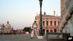 Seorang pekerja menyemprotkan cairan disinfektan di jalanan dekat San Marco, Venice, 6 April 2020. PM Italia Giuseppe Conte mengumumkan paket bantuan ekonomi tambahan senilai 434 miliar dolar bagi perusahaan-perusahaan Italia yang terimbas krisis virus corona. 