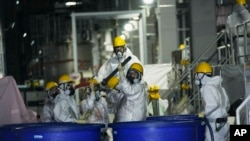 Sejumlah pria sedang bekerja menghilangkan bahan radioaktif dari air yang terkontaminasi di PLTN Fukushima Daiichi, dioperasikan oleh TEPCO, di kota Okuma, timur laut Jepang, Kamis, 3 Maret 2022. (Foto: AP)