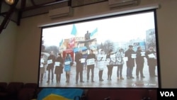 2014年在莫斯科的一场研讨会上，乌克兰活动人士展示国旗和乌克兰反政府示威活动视频。