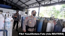 Para polisi menjaga distribusi oksigen di tempat isi ulang di tengah lonjakan kasus COVID-19 di Mengwi, Badung, Bali, 22 Juli 2021. (Foto: Fikri Yusuf/Antara Foto via Reuters