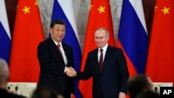 资料照：俄罗斯总统普京与中国领导人习近平在俄罗斯克里姆林宫举行会谈后在一个签字仪式上向媒体讲话后握手。（2023年3月21日）