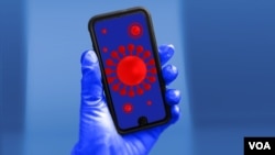 ILUSTRACIJA - Model koronavirusa na ekranu mobilnog telefona, koji drži ruka u rukavici 