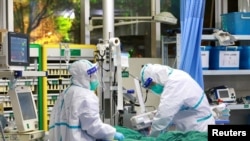 中国湖北省武汉大学中南医院的医生身穿防护服治疗一名新冠病毒肺炎病患。（2020年1月28日）