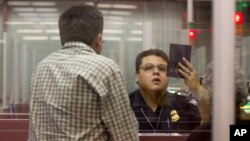 FILE - A Customs and Border Protection officer checks the passport of a non-resident visitor to the United States at McCarran International Airport, Dec. 13, 2011, in Las Vegas. 