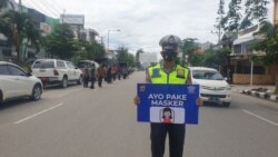 Seorang anggota Polisi kampanyekan ajakan memakai masker dalam sebuah operasi Yustisi yang digelar di Kota Palu. Kamis (24/09/2020) (Foto: VOA/Yoanes Litha)