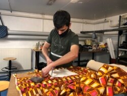 Pencari suaka Afghanistan, Haroon Sherzad memotong kain di sebuah bengkel kerja di Antony, dekat Paris, Prancis, 11 Juni 2021. (REUTERS/Michaela Cabrera)