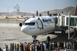 Warga Afghanistan naik ke atas sebuah pesawat saat mereka menunggu di bandara internasional Hamid Karzai di Kabul Senin 16 Agustus 2021, ketika ribuan orang mencoba melarikan diri dari rezim Taliban. (Foto: Wakil Kohsar / AFP)